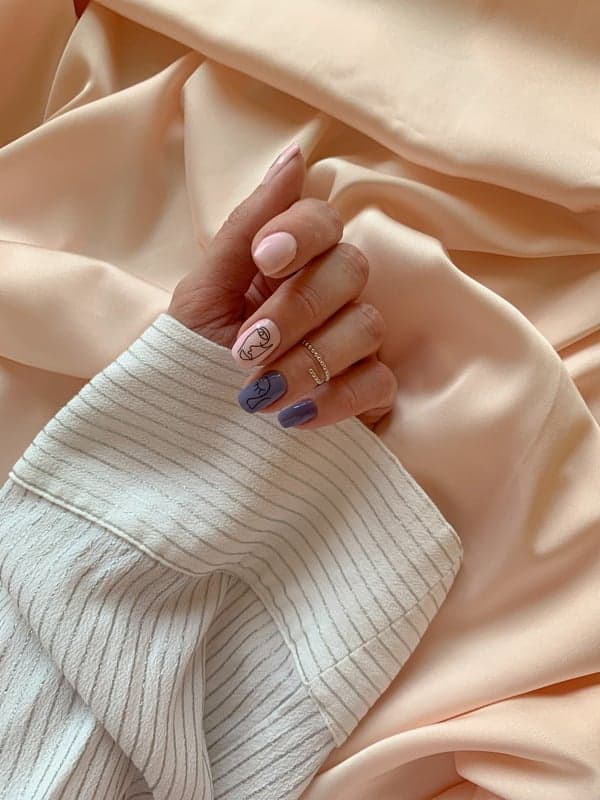 New nails with minimalist line art design, pink and purple manicure on a hand, elegant gel nail art, feminine nail styling, trendy nail design.